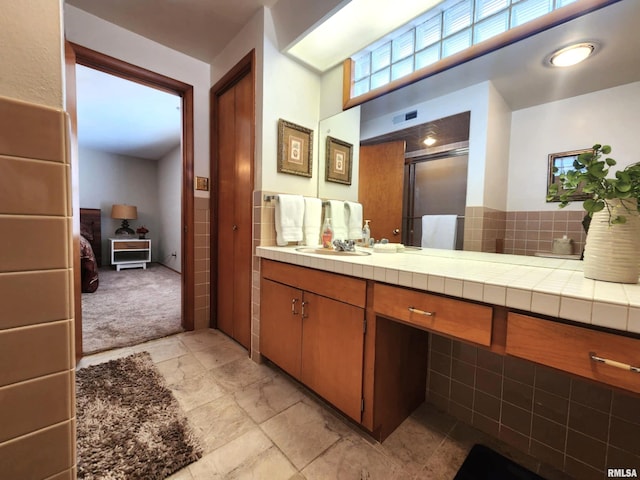 ensuite bathroom featuring a shower stall, ensuite bathroom, backsplash, and vanity