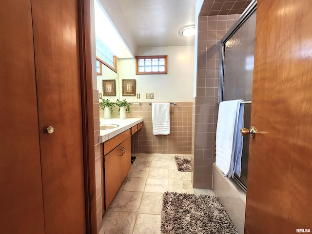 bathroom featuring wainscoting, enclosed tub / shower combo, tile walls, and vanity