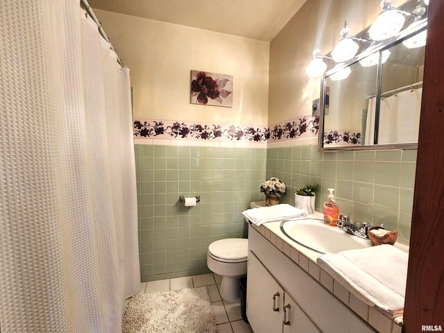 full bath with toilet, a wainscoted wall, tile walls, vanity, and tile patterned floors