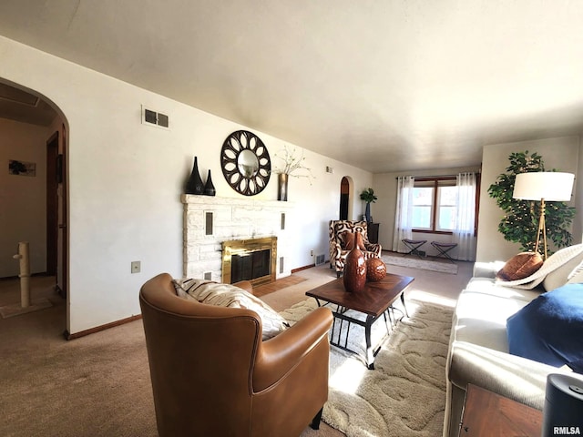 living room with arched walkways, visible vents, carpet flooring, a stone fireplace, and baseboards