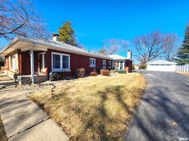 view of side of property with a chimney, fence, an outdoor structure, and brick siding