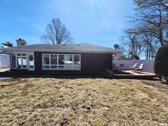 rear view of property featuring a lawn, a patio, a chimney, fence, and brick siding