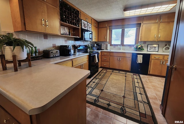 kitchen with tasteful backsplash, light countertops, a peninsula, and black appliances