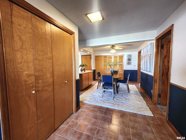 dining room with dark tile patterned floors, a ceiling fan, and a textured ceiling