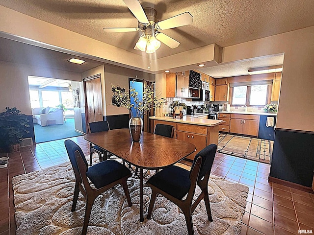 dining room with a textured ceiling, light tile patterned flooring, and a ceiling fan