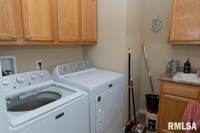 clothes washing area featuring a sink, washing machine and clothes dryer, and cabinet space