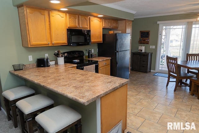 kitchen with a breakfast bar, light countertops, ornamental molding, a peninsula, and black appliances