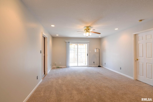 spare room featuring recessed lighting, light carpet, a textured ceiling, and baseboards