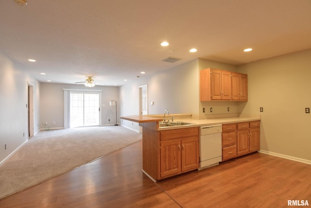 kitchen featuring recessed lighting, light countertops, open floor plan, a sink, and dishwasher