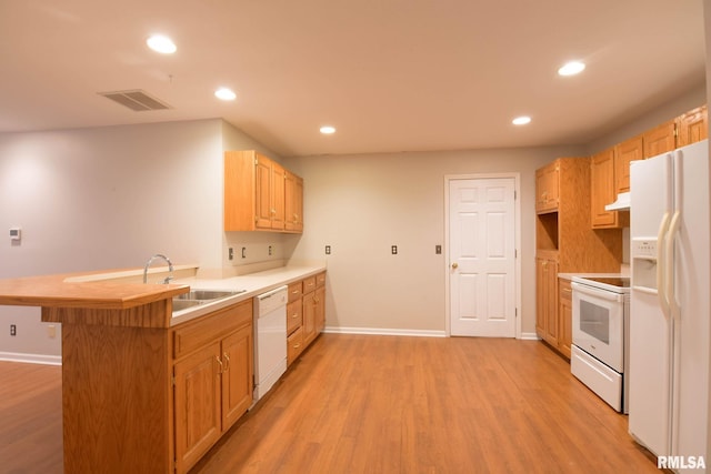 kitchen featuring white appliances, light wood finished floors, visible vents, a peninsula, and a sink