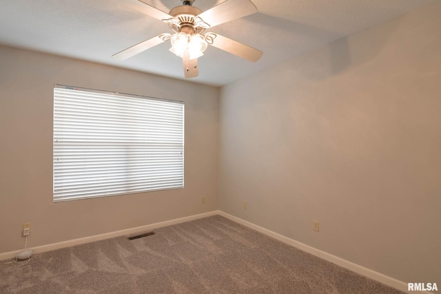 carpeted empty room featuring a ceiling fan, visible vents, and baseboards