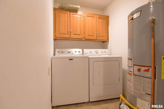 clothes washing area featuring gas water heater, washing machine and dryer, and cabinet space