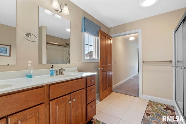 bathroom with double vanity, baseboards, tile patterned floors, a shower stall, and a sink