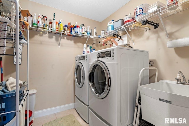 laundry room featuring light tile patterned floors, washing machine and dryer, a sink, laundry area, and baseboards