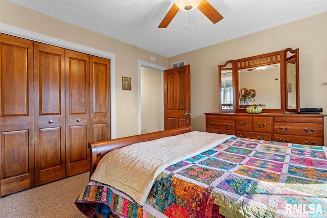 carpeted bedroom with a ceiling fan, a closet, visible vents, and a textured ceiling