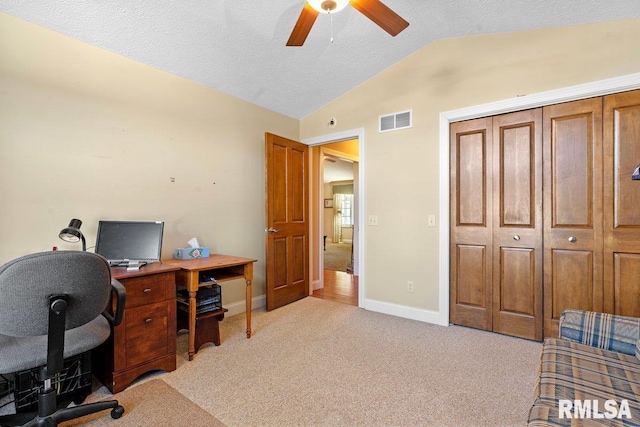 office area with a textured ceiling, light carpet, visible vents, baseboards, and vaulted ceiling