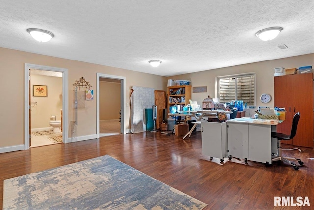 office area with a textured ceiling, baseboards, and wood finished floors