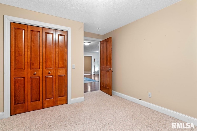 unfurnished bedroom featuring carpet, a closet, baseboards, and a textured ceiling