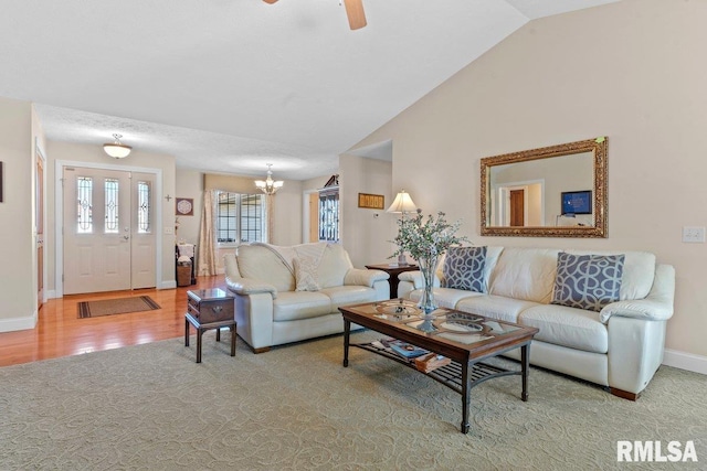 living area with ceiling fan with notable chandelier, lofted ceiling, baseboards, and wood finished floors