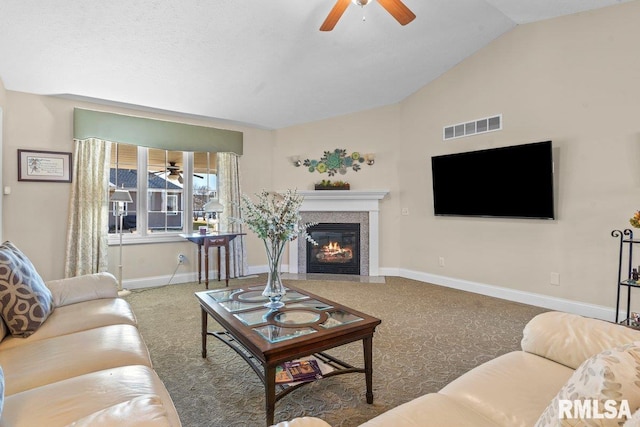 living area featuring baseboards, visible vents, lofted ceiling, ceiling fan, and a fireplace with flush hearth