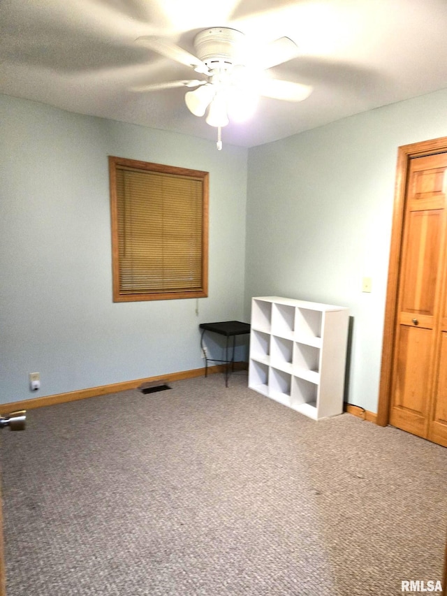 carpeted empty room with baseboards, visible vents, and a ceiling fan