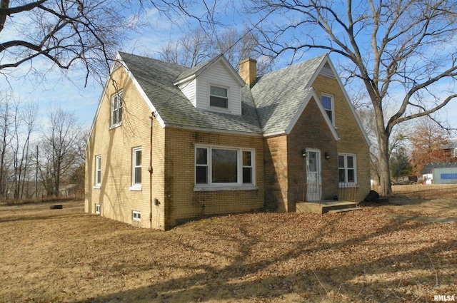 view of home's exterior featuring a shingled roof, brick siding, and a chimney