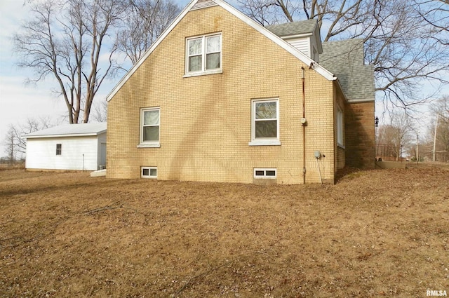 view of home's exterior with roof with shingles and brick siding