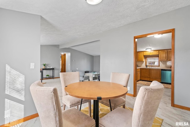 dining space with a textured ceiling, lofted ceiling, and baseboards