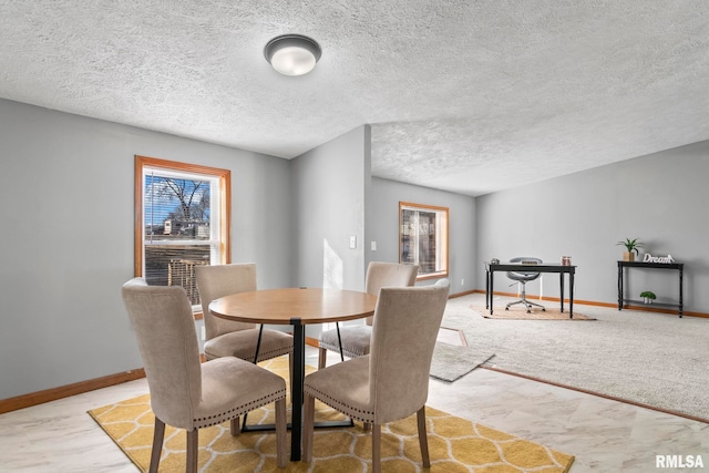 dining room featuring a textured ceiling and baseboards