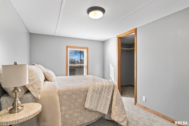 carpeted bedroom with baseboards and a walk in closet