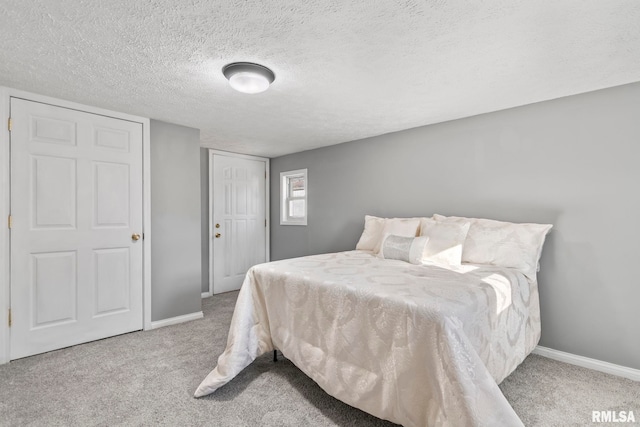 bedroom with a textured ceiling, a closet, carpet flooring, and baseboards