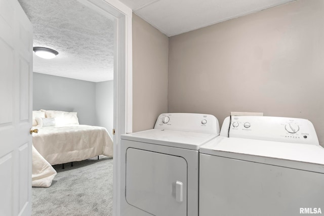 washroom with a textured ceiling, carpet floors, washer and clothes dryer, and laundry area