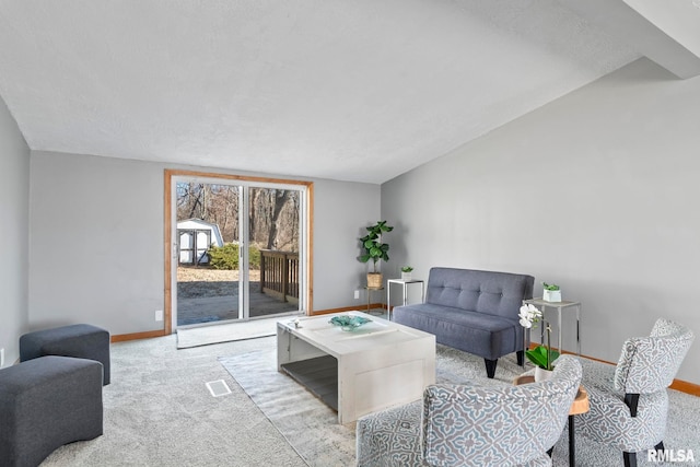 living area with baseboards, lofted ceiling, visible vents, and light colored carpet