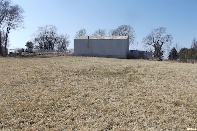 view of yard with fence, a pole building, and an outdoor structure