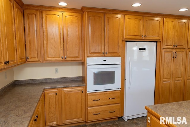 kitchen featuring white appliances, brown cabinets, and recessed lighting