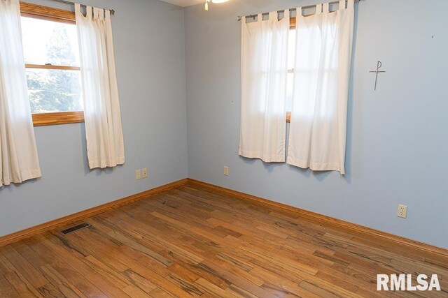 spare room featuring baseboards, visible vents, and wood finished floors