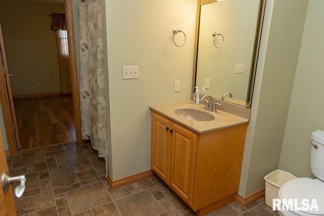 bathroom with toilet, stone finish floor, and vanity