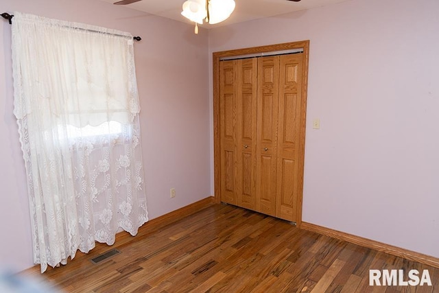 unfurnished bedroom with baseboards, visible vents, ceiling fan, wood finished floors, and a closet