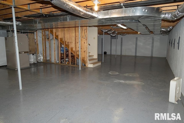 unfinished basement featuring stairway and heating unit