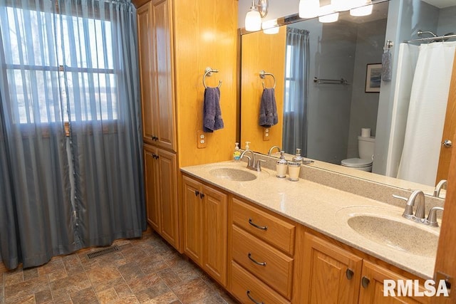 full bathroom with stone finish floor, visible vents, a sink, and toilet