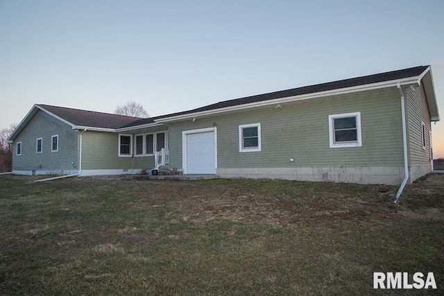 rear view of property with a lawn and an attached garage