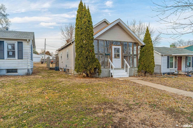 view of front of home with entry steps, a sunroom, and a front lawn