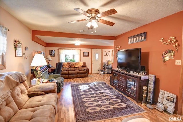 living area with ceiling fan, a textured ceiling, and wood finished floors