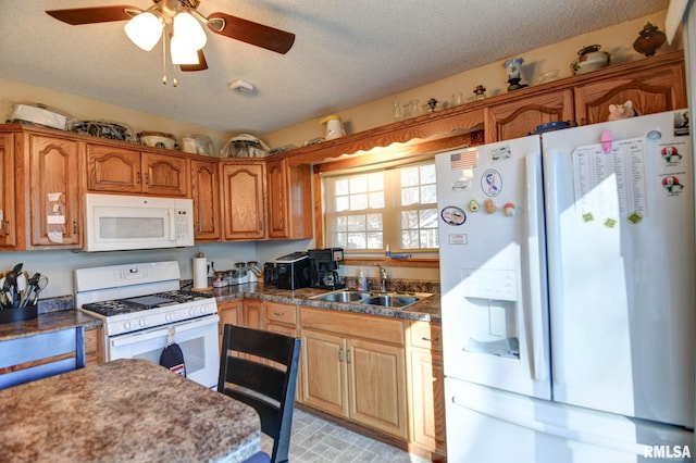 kitchen with brown cabinets, a ceiling fan, a sink, a textured ceiling, and white appliances