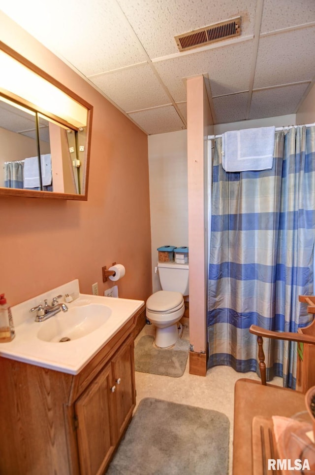 bathroom with a paneled ceiling, visible vents, vanity, and toilet