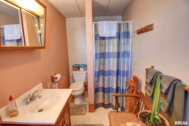 full bathroom featuring toilet, a shower with curtain, a drop ceiling, and vanity