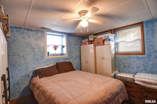 bedroom with a ceiling fan, a paneled ceiling, visible vents, and wallpapered walls