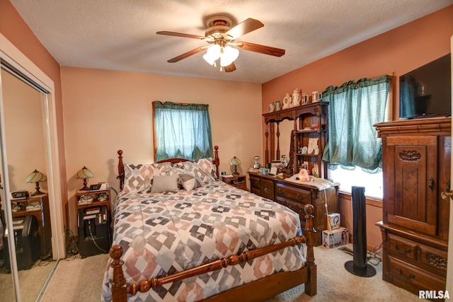 bedroom with light carpet, a closet, a textured ceiling, and a ceiling fan