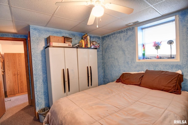 bedroom with wallpapered walls, visible vents, a ceiling fan, a paneled ceiling, and carpet floors