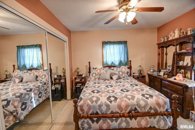 bedroom featuring a textured ceiling, a ceiling fan, a closet, and light colored carpet